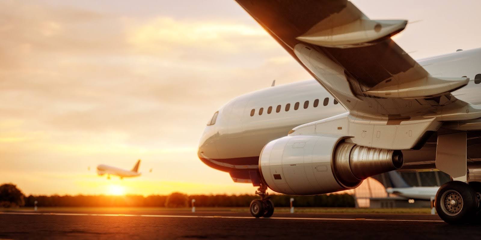 Commercial airplane standing on the airport runway at sunset.